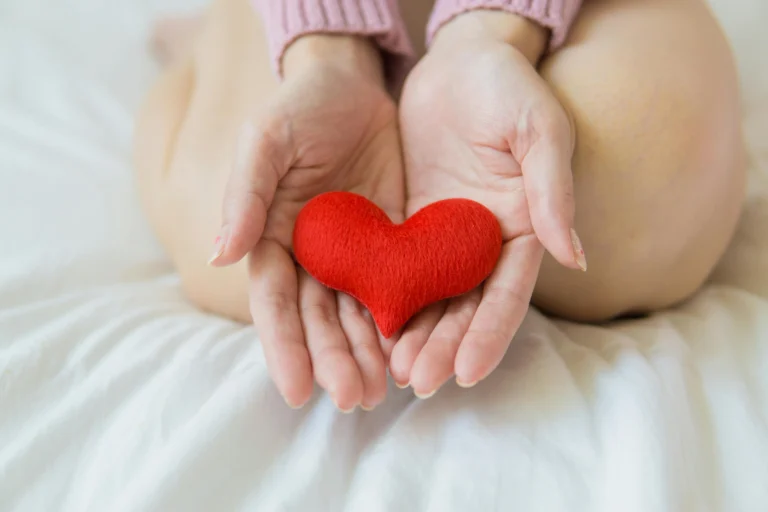 a woman holding a red heart in her hands and asking is cardamom good for periods"