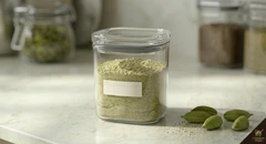 Ground cardamom powder in small airtight glass jar with date label