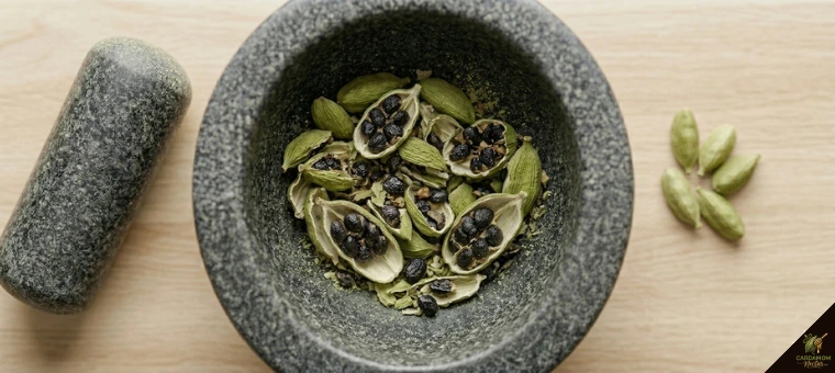 Freshly crushing green cardamom pods with mortar exposing black seeds for digestive tea