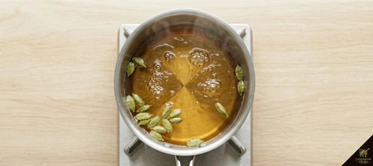 Cardamom pods simmering in water turning golden for after-meal digestive tea